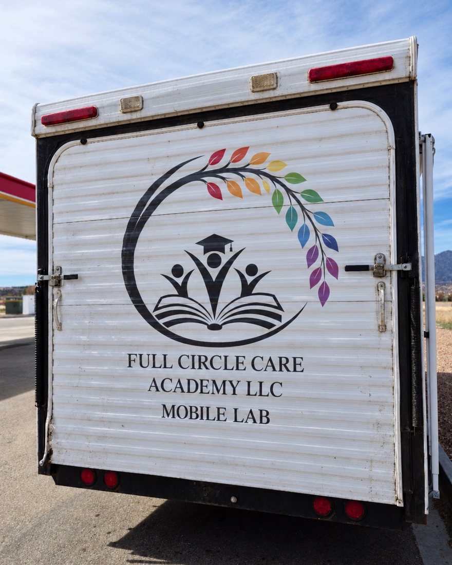 The back of the mobile lab trailer, lettered Full Circle Care Academy LLC Mobile Lab, parked with mountains behind it.