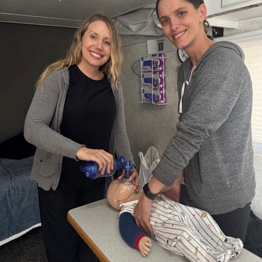 An instructor and a student practicing infant resuscitation skills on a manikin inside the mobile skills lab.